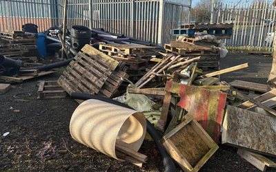 Pallets, pipes and timber dumped in a fenced yard