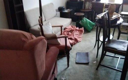 Living room with armchairs, sofa and dining chairs waiting to be cleared