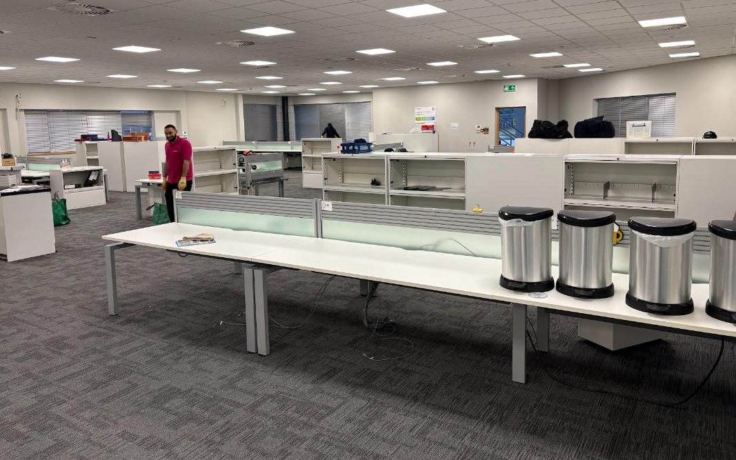 Open plan office being cleared, with desks and storage units emptied